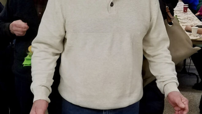 Tom Beatty smiles in front of his cake at his retirement party