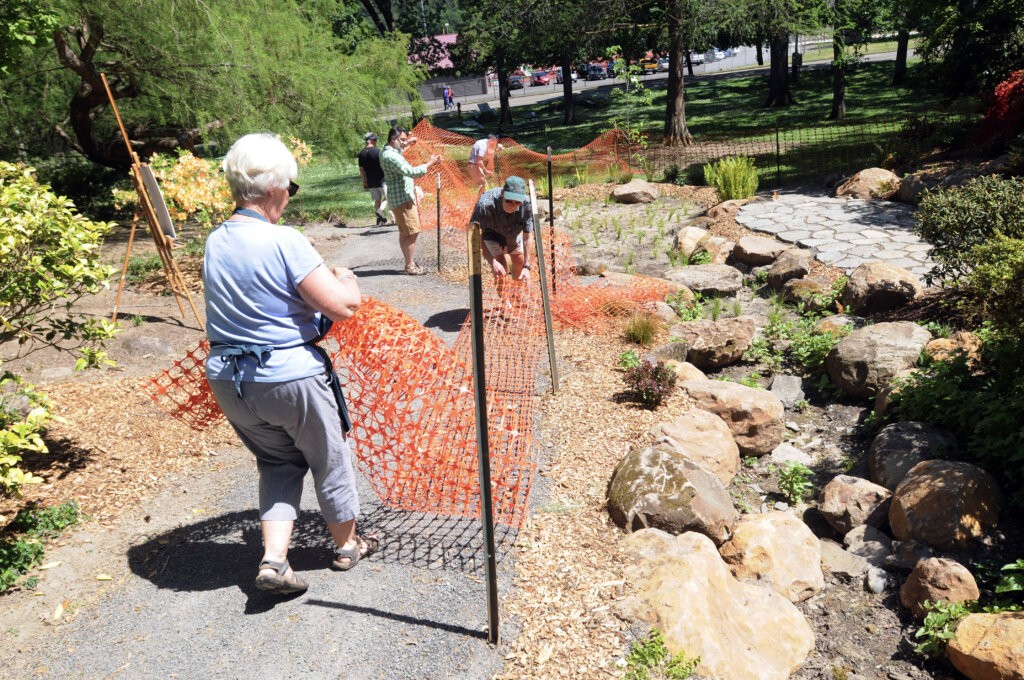 Several people remove orange fencing as part of the Ravine public opening event.